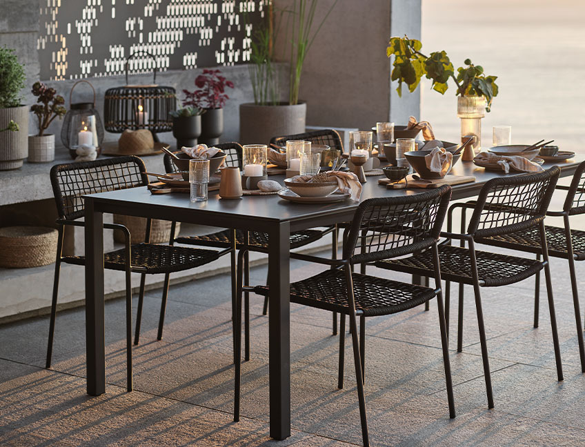 Mesa de jardín y sillas de jardín con la mesa puesta para cenar en una terraza al atardecer