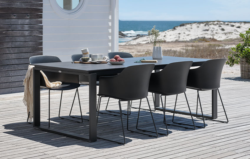 Mesa de jardín grande y sillas en una terraza frente al mar