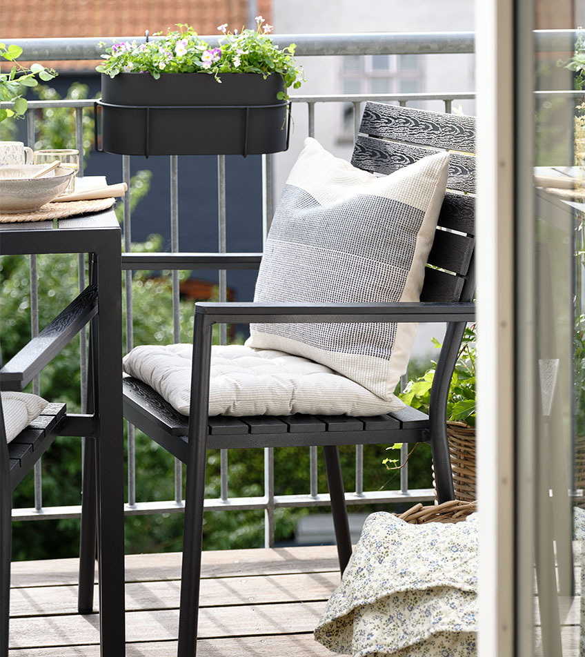 Silla de jardín apilable negra con cojines en un balcón